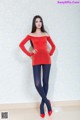 A woman in a red top and blue tights posing for a picture.