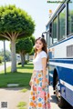 A woman standing in front of a blue and white bus.