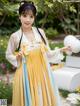 A woman in a yellow and blue hanbok is posing for a picture.