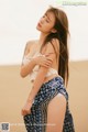 A woman in a white top and blue skirt posing in the desert.