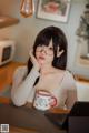 A woman sitting at a table with a laptop and a cup of coffee.