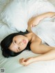 A woman laying on a bed with white sheets and pillows.