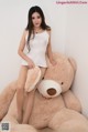 A woman sitting on top of a large teddy bear.