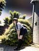 A girl in a school uniform leaning against a wall.