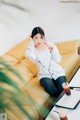 A woman sitting on a yellow couch next to a table.