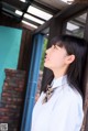 A woman in a white shirt leaning against a wooden door.