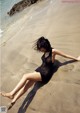 A woman in a black dress laying on the beach.