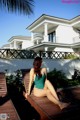 A woman in a green bathing suit sitting on a wooden deck.